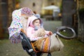 Cute little beautiful baby girl sitting in the pram or stroller on autumn day. Happy smiling child in warm clothes Royalty Free Stock Photo