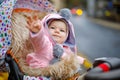 Cute little beautiful baby girl sitting in the pram or stroller on autumn day. Happy smiling child in warm clothes Royalty Free Stock Photo