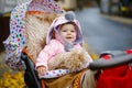 Cute little beautiful baby girl sitting in the pram or stroller on autumn day. Happy smiling child in warm clothes Royalty Free Stock Photo