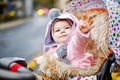 Cute little beautiful baby girl sitting in the pram or stroller on autumn day. Happy smiling child in warm clothes Royalty Free Stock Photo