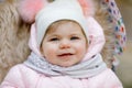 Cute little beautiful baby girl sitting in the pram or stroller on cold autumn, winter or spring day. Happy smiling Royalty Free Stock Photo