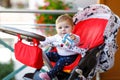 Cute little beautiful baby girl sitting in the pram or stroller and waiting for mom. Happy smiling child with blue eyes. Royalty Free Stock Photo