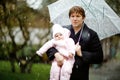 Cute little beautiful baby girl and young father on cold day with sleet, rain and snow. Happy smiling child in warm