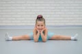 Cute little beautiful girl doing splits at ballet class. Young happy ballerina in blue dress stretching, smiling and Royalty Free Stock Photo