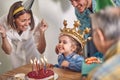 Cute little birthday girl in front of birthday cake with lit candles, feeling super excited with her mother father and grandfather Royalty Free Stock Photo