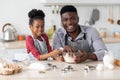 Cute little black girl helping her father with cookies baking Royalty Free Stock Photo