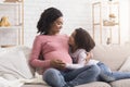 Cute little black girl and her pregnant mom embracing at home Royalty Free Stock Photo