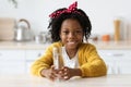 Cute Little Black Girl Holding Glass With Water While Sitting In Kitchen Royalty Free Stock Photo