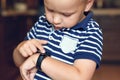 Cute little blond boy with blue eyes points out to digital fitness tracker on his wrist. Serious expression, strong emotions, chil