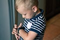 Cute little blond boy with blue eyes points out to digital fitness tracker on his wrist.