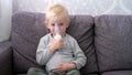 Cute little blond boy spraying respiratory diseases at home.