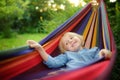 Cute little blond caucasian boy enjoy and having fun with multicolored hammock in backyard or outdoor playground. Summer active Royalty Free Stock Photo