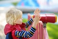 Cute little blond caucasian boy, kid or child looking through binoculars on playground outdoors Royalty Free Stock Photo