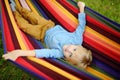 Cute little blond caucasian boy relaxing and having fun in multicolored hammock in backyard or outdoor playground. Summer active