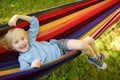 Cute little blond caucasian boy relaxing and having fun in multicolored hammock in backyard or outdoor playground. Summer active Royalty Free Stock Photo