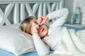 Cute little blond caucasian girl awakening at bed in morning. Child wake up early to go to school. Stretching and Royalty Free Stock Photo