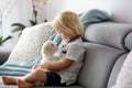 Cute little blond child, toddler boy, playing with white puppy maltese dog Royalty Free Stock Photo