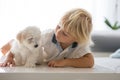 Cute little blond child, toddler boy, playing with white puppy maltese dog Royalty Free Stock Photo