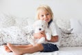 Cute little blond child, toddler boy, reading book with white puppy maltese dog Royalty Free Stock Photo