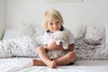 Cute little blond child, toddler boy, reading book with white puppy maltese dog Royalty Free Stock Photo