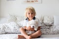 Cute little blond child, toddler boy, reading book with white puppy maltese dog Royalty Free Stock Photo