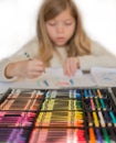Cute little blond girl is drawing by colorful pencils , box of pencils on the foreground Royalty Free Stock Photo