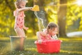 The cute little blond girls playing with water splashes on the field in summer Royalty Free Stock Photo