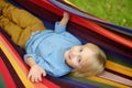 Cute little blond white boy enjoy and having fun with multicolored hammock in backyard or outdoor playground. Summer outdoors Royalty Free Stock Photo