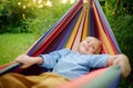 Cute little blond white boy enjoy and having fun with multicolored hammock in backyard or outdoor playground. Summer outdoors Royalty Free Stock Photo