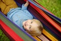 Cute little blond white boy enjoy and having fun with multicolored hammock in backyard or outdoor playground. Summer outdoors Royalty Free Stock Photo