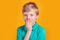 Cute little blonde boy looking suprised on yellowbackground Royalty Free Stock Photo