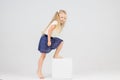 Cute little blonde girl climbs white cube