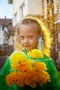 Cute little blonde girl in green raincoat with yellow flowers on a green lawn under rain drops in a summer sunny day Royalty Free Stock Photo