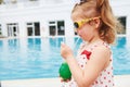 Cute little blonde at the pool and holding a child`s cocktail