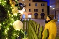 Cute little boy admiring large ornate Christmas tree on square of Kotor old town at dusk. Xmas vacations in Montenegro. Winter