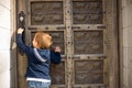 Cute little boy baby knocking on old door