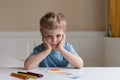 Cute little boy with blond hair and blue T-shirt draws colored pencils at home Royalty Free Stock Photo