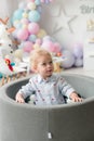 Cute little boy with blond hair on his birthday at a children`s party with balloons in the pool with balls. Children`s party. Royalty Free Stock Photo