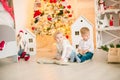 Cute little boy with blond hair plays with little girl in a bright room decorated with Christmas garlands