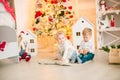 Cute little boy with blond hair plays with little girl in a bright room decorated with Christmas garlands