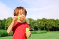 Cute little boy blowing bubbles in park on sunny day Royalty Free Stock Photo