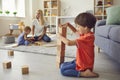 Cute little boy building wood block tower with small brother and mommy in background Royalty Free Stock Photo