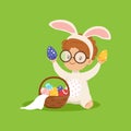 Cute little boy with bunny ears and rabbit costume playing with basket with painted eggs, kid having fun on Easter egg Royalty Free Stock Photo