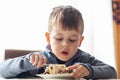 Cute little boy in cafe eat a big piece of cake with a fork. Desserts for kids