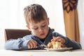 Cute little boy in cafe eat a big piece of cake with a fork. Desserts for kids
