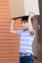 Cute little boy carrying cardboard box