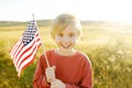 Cute little boy celebrating of July, 4 Independence Day of USA at sunny summer sunset. Child running with american flag of United Royalty Free Stock Photo