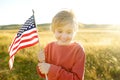 Cute little boy celebrating of July, 4 Independence Day of USA at sunny summer sunset. Child running with american flag of United Royalty Free Stock Photo