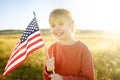 Cute little boy celebrating of July, 4 Independence Day of USA at sunny summer sunset. Child running with american flag of United Royalty Free Stock Photo