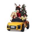 Cute little boy with Christmas tree, bunny toy and gift boxes driving children`s car on white background Royalty Free Stock Photo